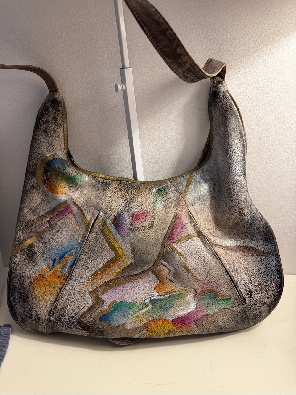 Distressed leather hobo bag with colorful abstract design on front and back.